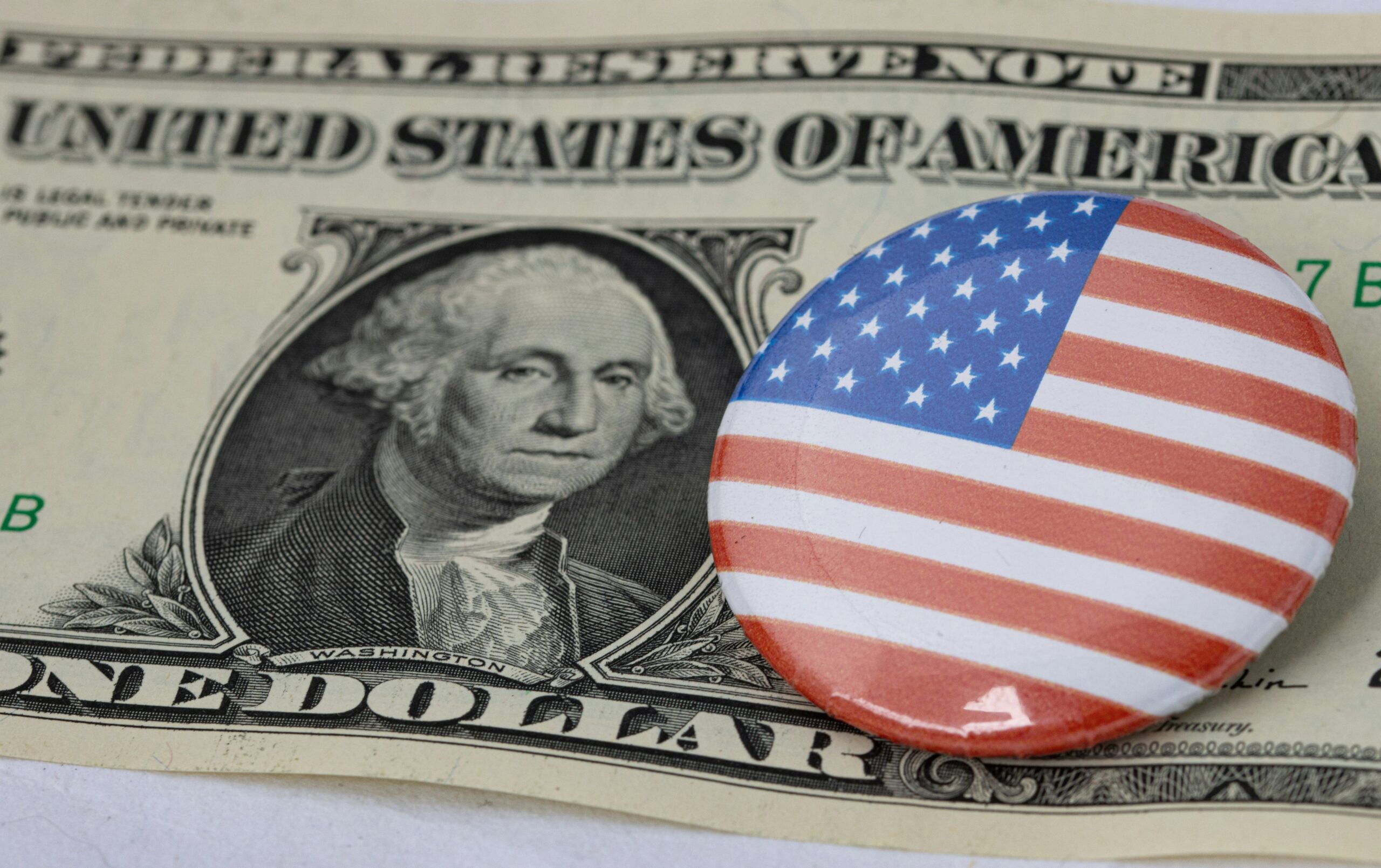 Billete de un dólar y botón con George Washington, símbolos del papá estado.